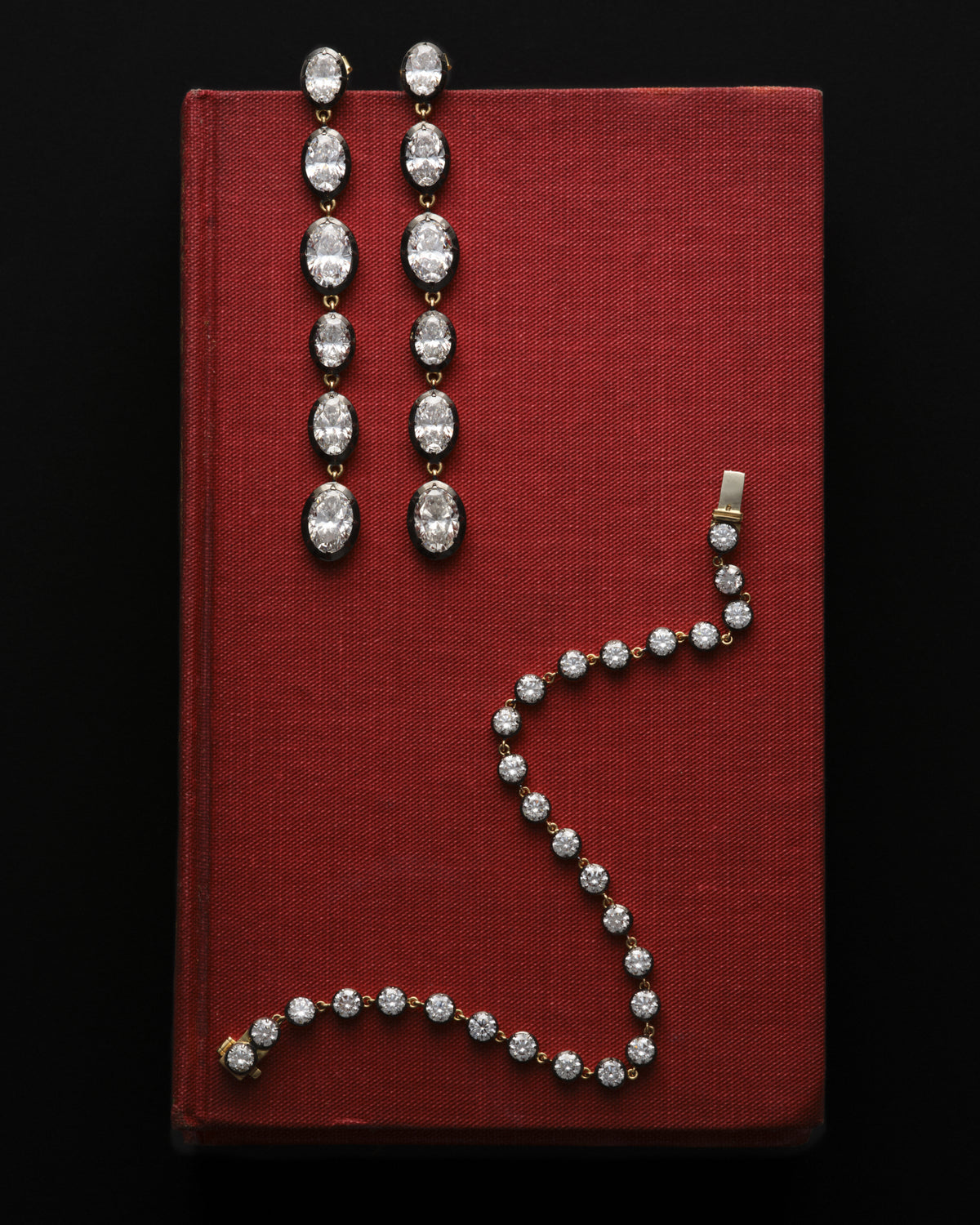 Bouton oval dangle earrings and Le Marais bracelet on a red cloth book