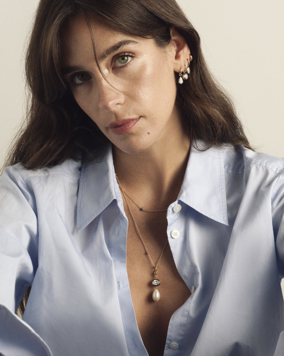 Model in a blue shirt wearing layered necklaces