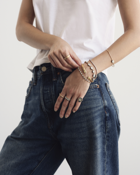 Stacked De La Paix gold and lab-grown diamond bracelets worn with denim
