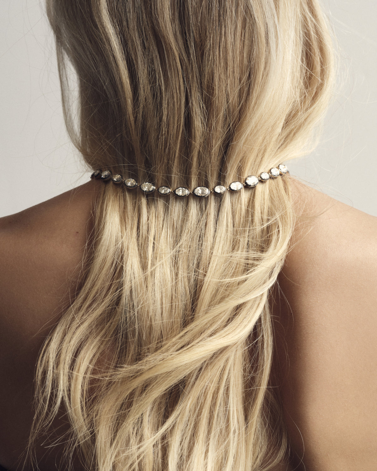 Oval diamond necklace worn over long blonde hair