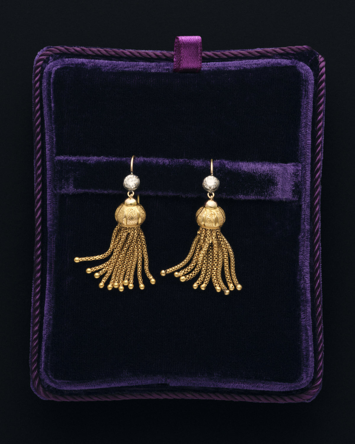 Gold tassel earrings in a purple velvet box